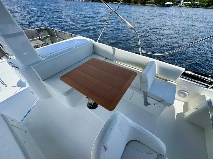  Yacht Photos Pics 2025 Beneteau Swift Trawler 41 Fly deck with seating and wooden table, overlooking water.