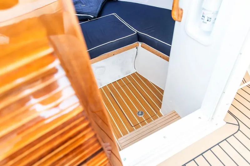 Given To Fly Yacht Photos Pics 2021 Hunt Yachts Harrier 26 interior with wooden flooring and navy seating.