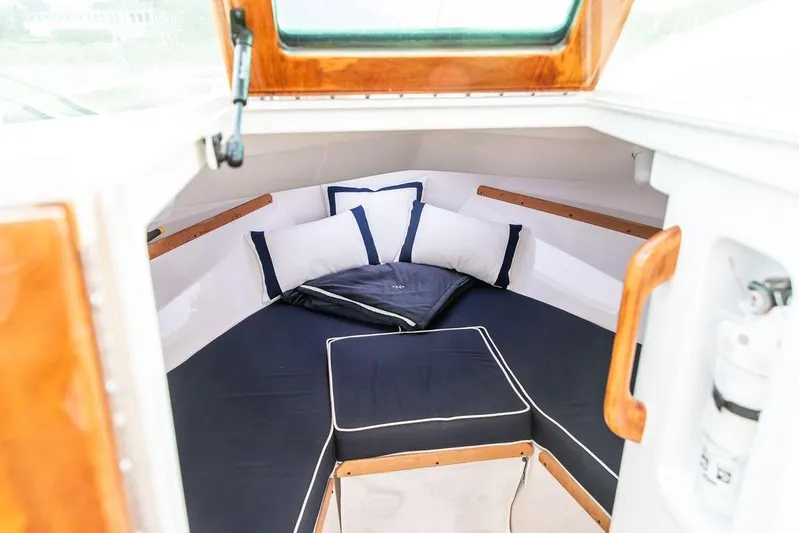 Given To Fly Yacht Photos Pics 2021 Hunt Yachts Harrier 26 cabin interior with cozy bedding and wooden accents.