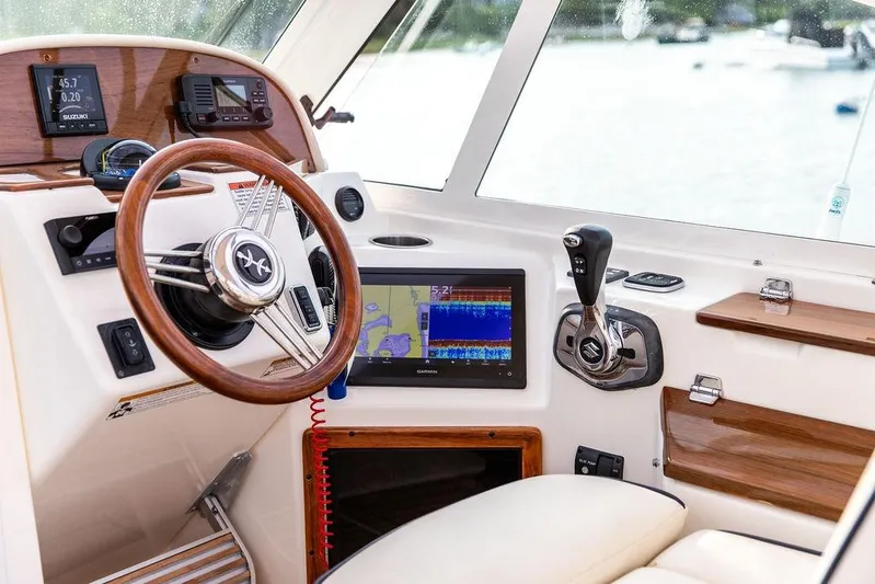 Given To Fly Yacht Photos Pics 2021 Hunt Yachts Harrier 26 helm with wooden steering wheel and modern navigation equipment.