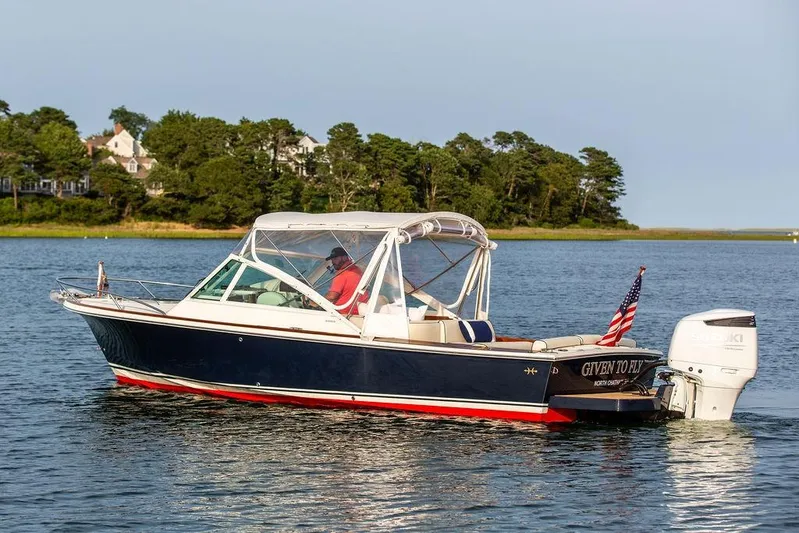 Given To Fly Yacht Photos Pics 2021 Hunt Yachts Harrier 26 cruising on a serene lake with lush green shoreline.