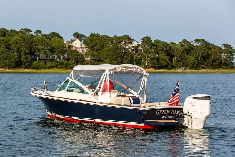 Given To Fly Yacht Photos Pics 2021 Hunt Yachts Harrier 26 cruising on a serene lake with lush green shoreline.