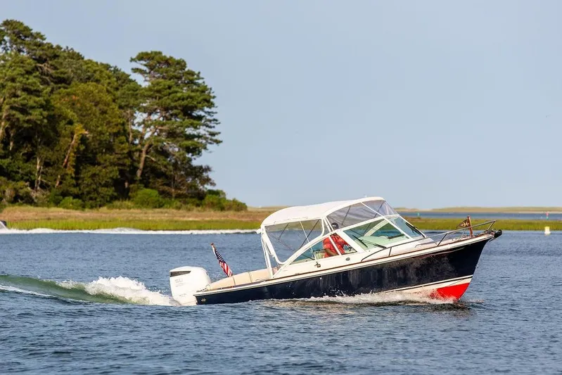 Given To Fly Yacht Photos Pics 2021 Hunt Yachts Harrier 26 cruising on a serene lake near lush greenery.