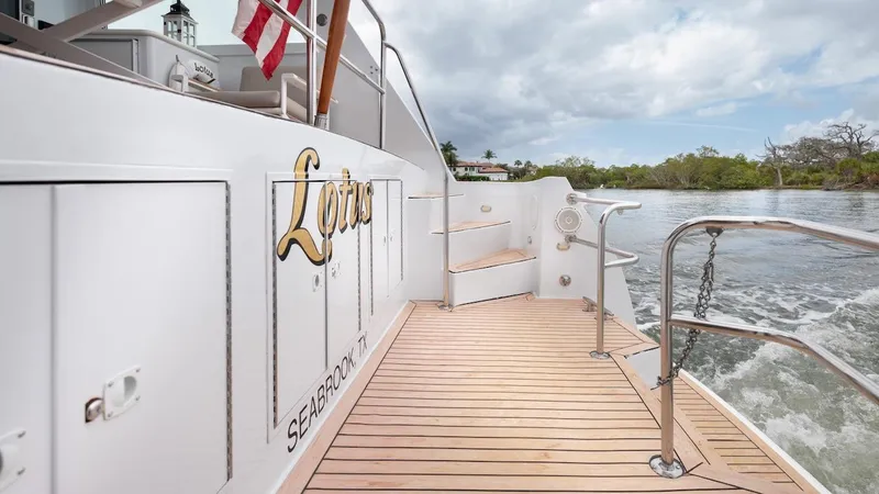  Yacht Photos Pics 1998 Hatteras 74 Sport Deck Motor Yacht, teak deck, American flag, serene waterway backdrop.