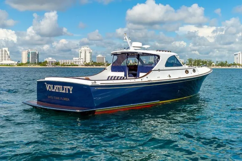 Volatility Yacht Photos Pics Blue San Juan SJ 38 yacht from 2003 on water, cityscape in background.