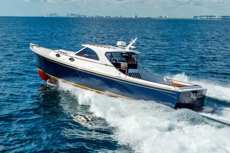Volatility Yacht Photos Pics 2003 San Juan SJ 38 boat cruising on open water with city skyline in background.