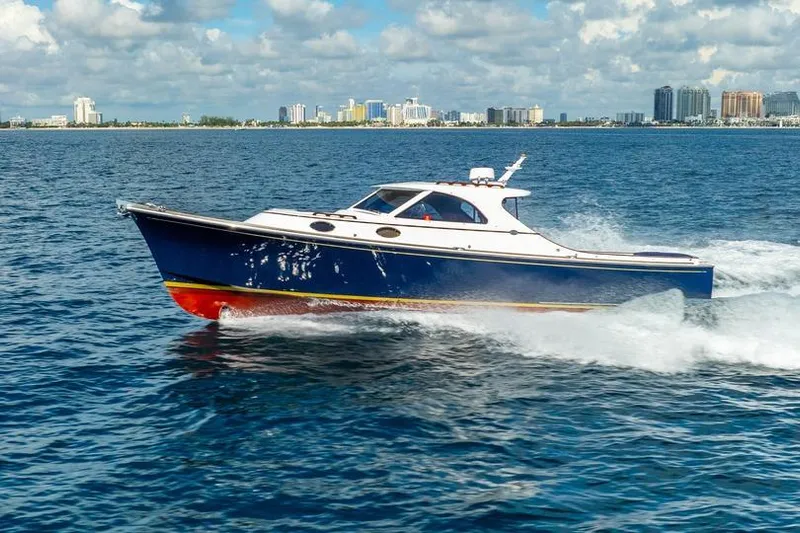 Volatility Yacht Photos Pics 2003 San Juan SJ 38 boat cruising on open water with city skyline in background.