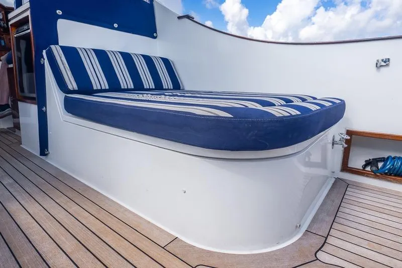 Volatility Yacht Photos Pics Blue-striped cushioned seating on 2003 San Juan SJ 38 boat deck, under a partly cloudy sky.