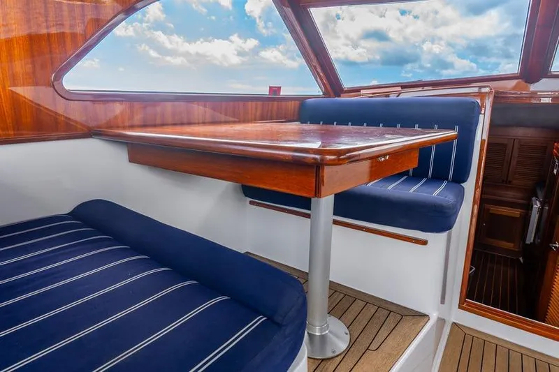 Volatility Yacht Photos Pics 2003 San Juan SJ 38 interior with wooden table, blue cushioned seating, and scenic window view.