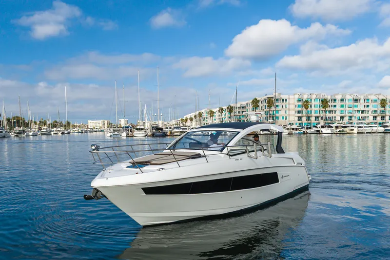 Lux Life Yacht Photos Pics 2017 Cruisers Yachts 39 Express Coupe in a marina, clear sky, modern buildings.