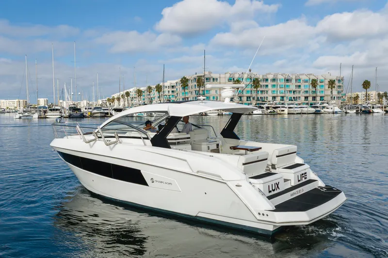 Lux Life Yacht Photos Pics 2017 Cruisers Yachts 39 Express Coupe in marina, clear sky, modern waterfront buildings.