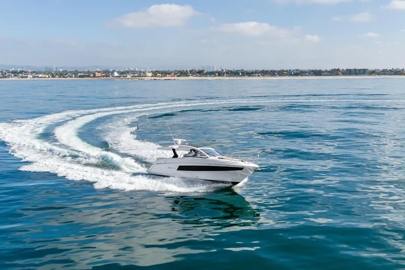 Lux Life Yacht Photos Pics 2017 Cruisers Yachts 39 Express Coupe cruising on open water, near coastal cityscape.