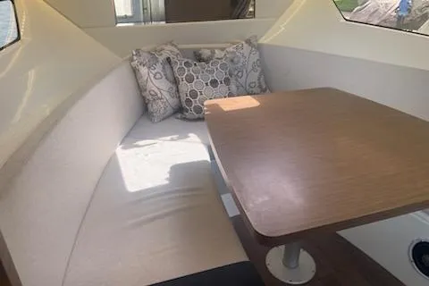  Yacht Photos Pics 2019 Jeanneau 9.0 WA interior with cozy seating and wooden table.