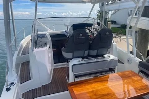  Yacht Photos Pics 2019 Jeanneau 9.0 WA boat with dual seats and wooden table, docked by the water.