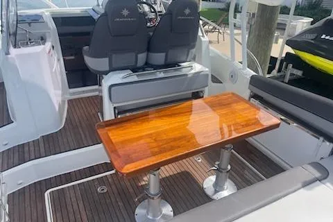  Yacht Photos Pics 2019 Jeanneau 9.0 WA boat interior with wooden table and seating area.