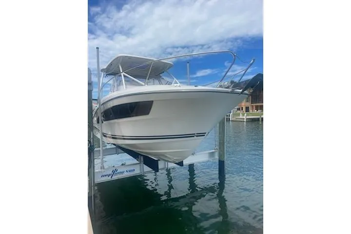  Yacht Photos Pics 2019 Jeanneau 9.0 WA boat on lift, docked by waterfront homes under blue sky.