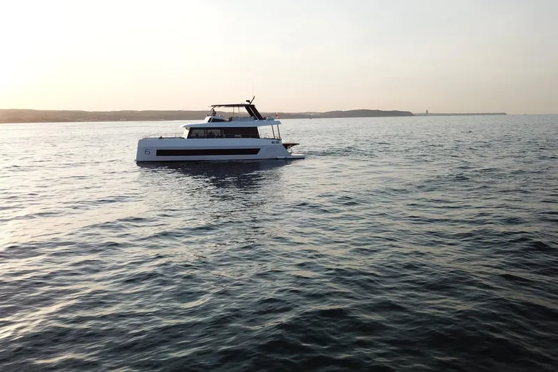  Yacht Photos Pics 2026 Moon Yachts 6ty sailing on calm waters at sunset.