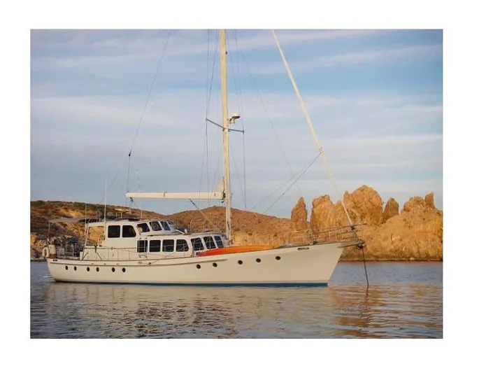  Yacht Photos Pics Custom Centre Cockpit Pilot House Steel Cutter Motorsailer, 70 ft, 1991, anchored near rocky coastline.