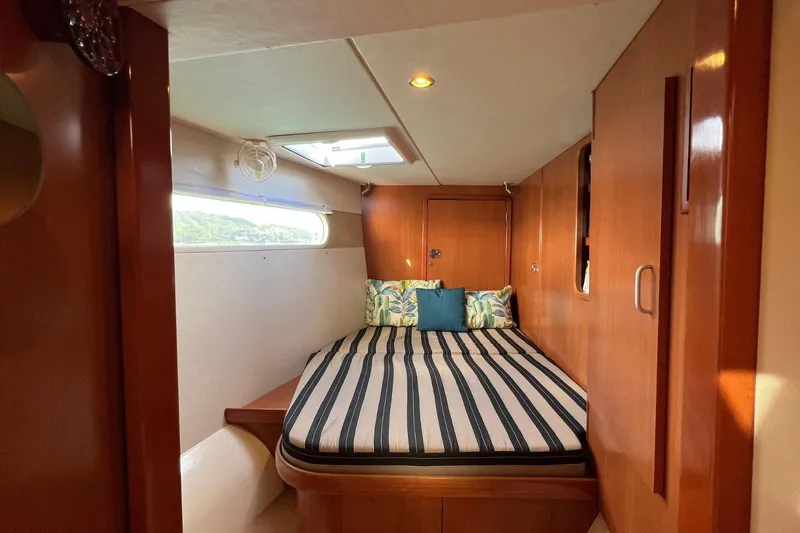 Mahi Mahi Yacht Photos Pics Cozy cabin interior of 2009 Leopard 46 yacht with striped bedding and wooden finish.