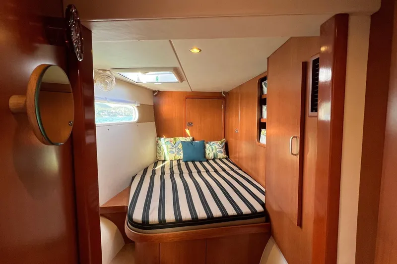 Mahi Mahi Yacht Photos Pics Cozy cabin interior of 2009 Leopard 46 yacht with striped bedding and wooden finish.