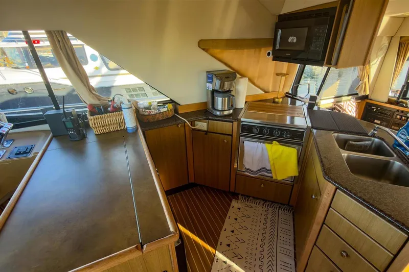 Daybreak Yacht Photos Pics Interior of 2002 Bayliner 3988 Command Bridge Motoryacht kitchen with appliances and wooden cabinetry.