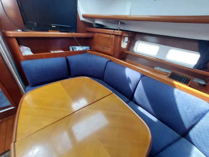 Wind & Wine Yacht Photos Pics Interior of 2002 Beneteau Oceanis 42CC yacht with blue seating and wooden table.