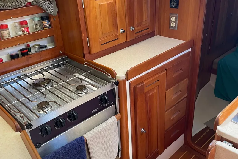 Maeve Yacht Photos Pics Wooden yacht kitchen with stove, spice rack, and cabinetry in a 2004 Tartan 3700.
