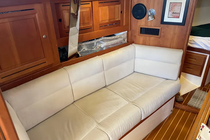 Maeve Yacht Photos Pics Interior of 2004 Tartan 3700 yacht with beige sofa and wooden cabinetry.