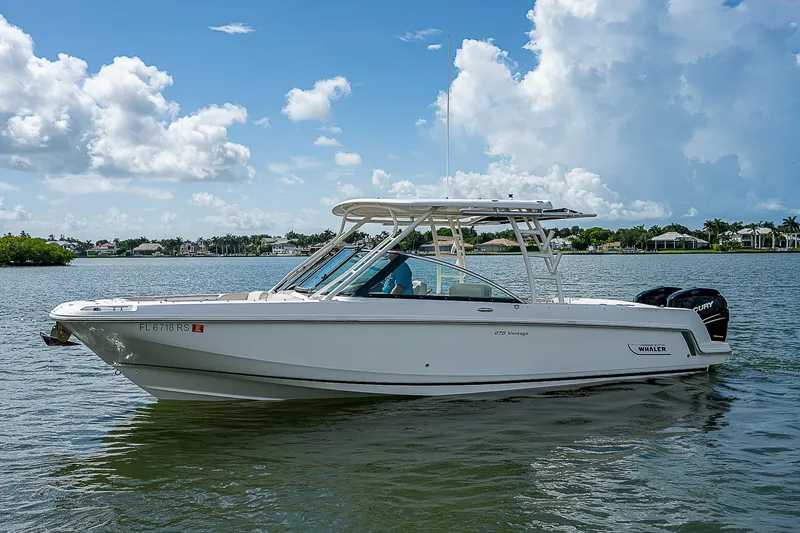  Yacht Photos Pics 2018 Boston Whaler 270 Vantage boat on a calm lake under a blue sky.