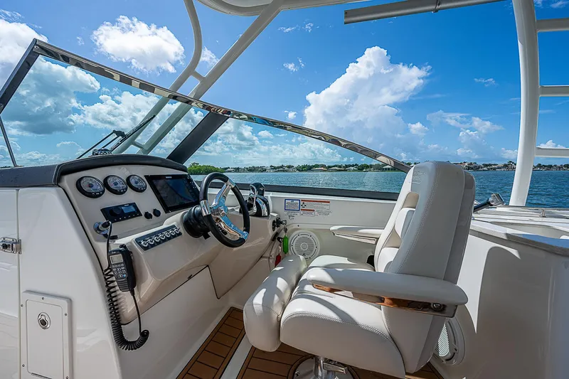  Yacht Photos Pics 2018 Boston Whaler 270 Vantage boat cockpit with steering wheel and controls, under blue sky.