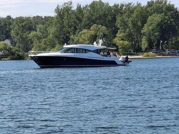  Yacht Photos Pics 2020 Tiara Yachts 53 Coupe on a serene lake with lush green trees.