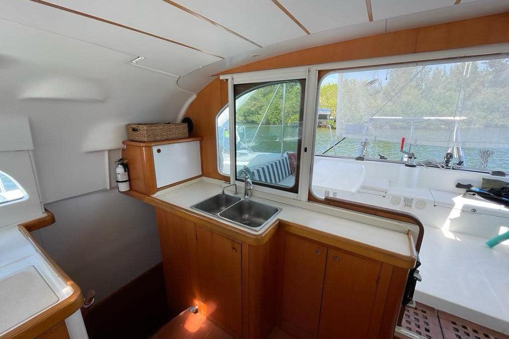 Interior of 2006 Lagoon 410-S2 catamaran with wooden cabinetry and a stainless steel sink.