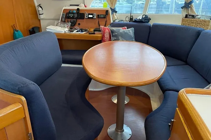 Yolo Yacht Photos Pics Interior of 2006 Lagoon 410-S2 catamaran with blue seating and wooden table.