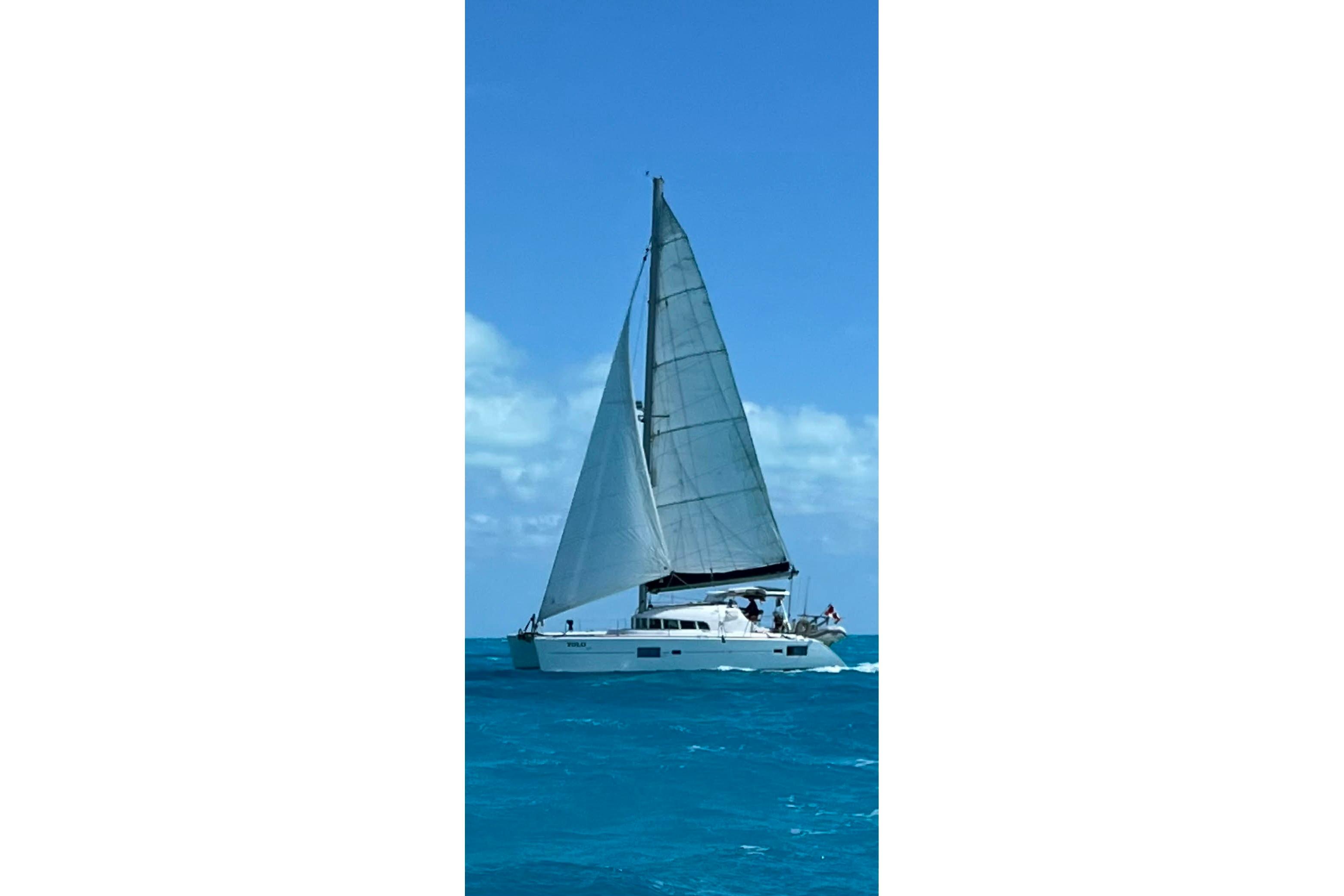 2006 Lagoon 410-S2 catamaran sailing on clear blue ocean waters.