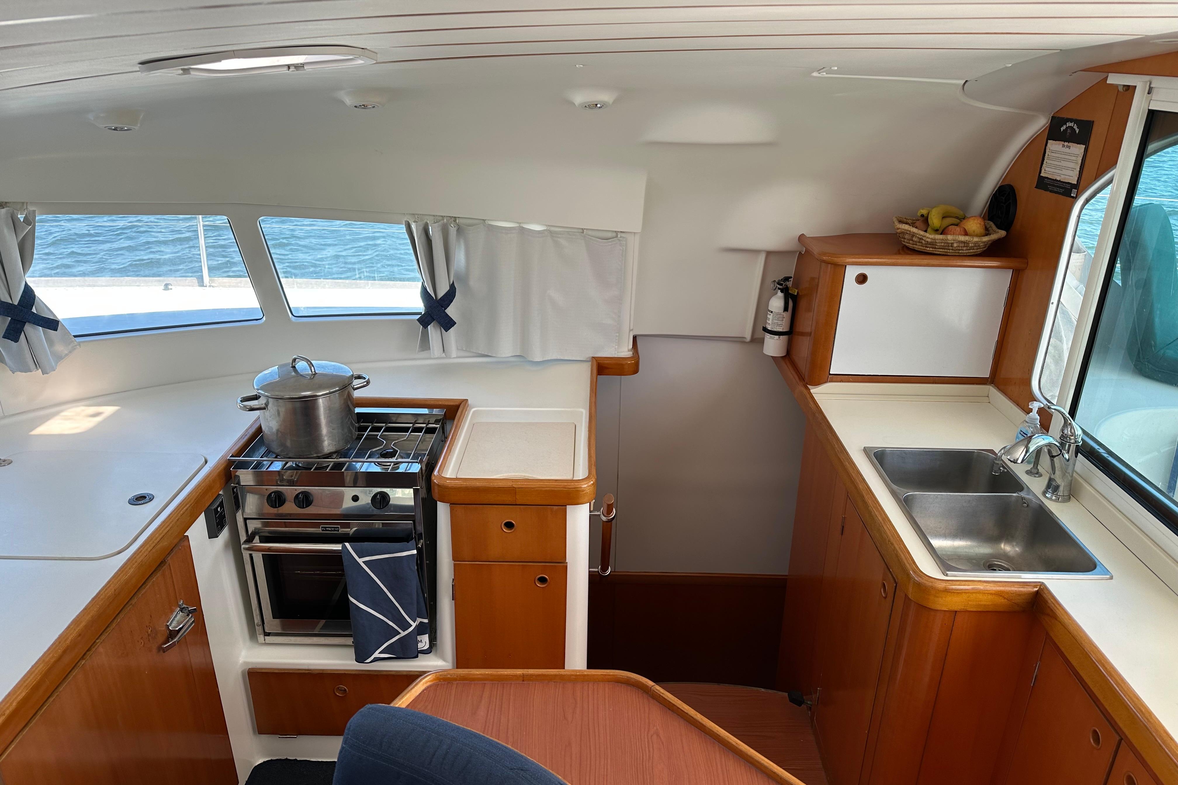 Interior of 2006 Lagoon 410-S2 yacht kitchen with stove, sink, and wooden cabinetry.