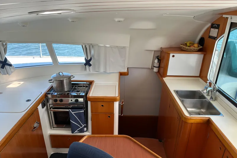 Yolo Yacht Photos Pics Interior of 2006 Lagoon 410-S2 yacht kitchen with stove, sink, and wooden cabinetry.