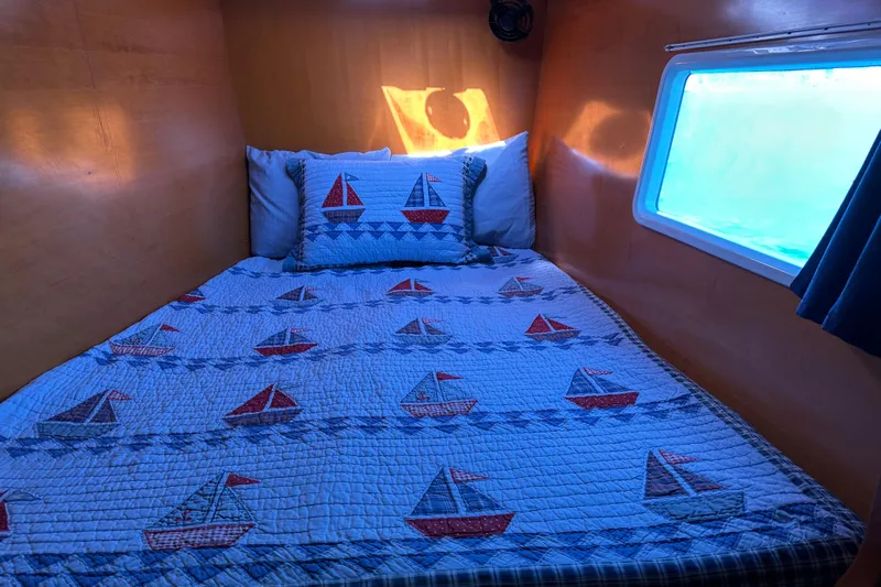 Yolo Yacht Photos Pics Cozy cabin bed in 2006 Lagoon 410-S2 with nautical-themed quilt and window view.