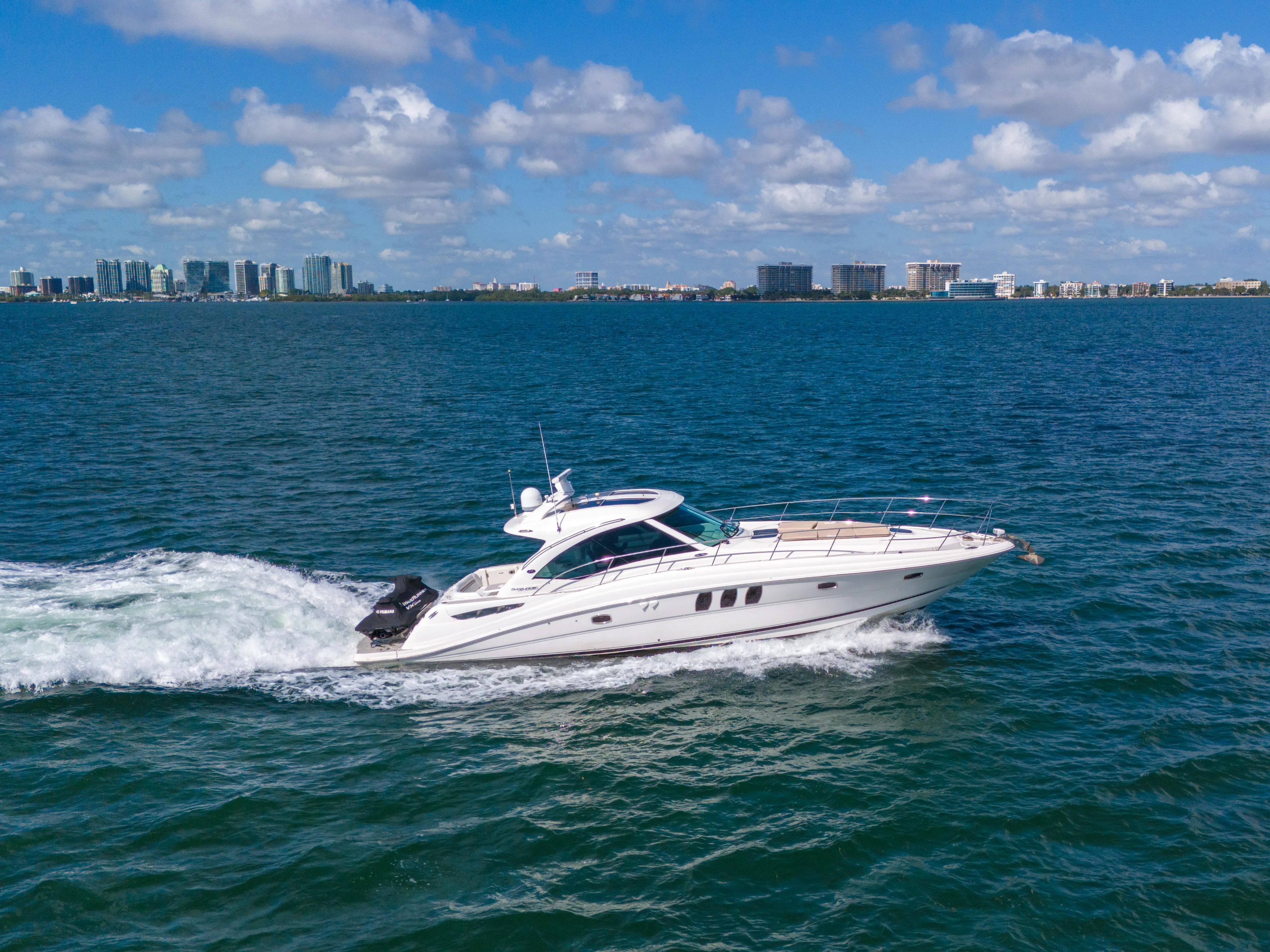  Yacht Photos Pics Sea Ray 500 Sundancer 2010 cruising on blue ocean with city skyline in background.