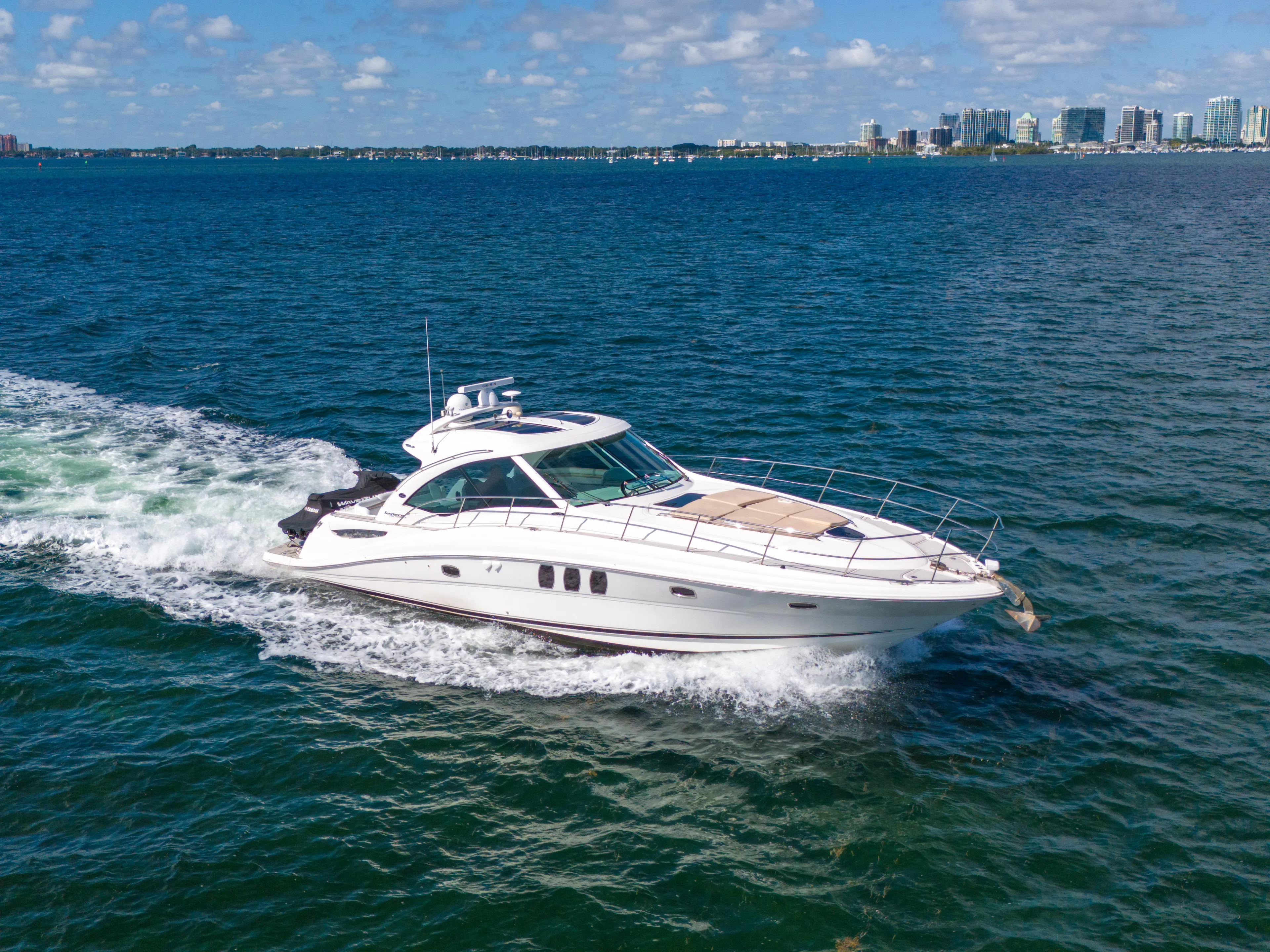  Yacht Photos Pics 2010 Sea Ray 500 Sundancer cruising on blue ocean with city skyline in background.