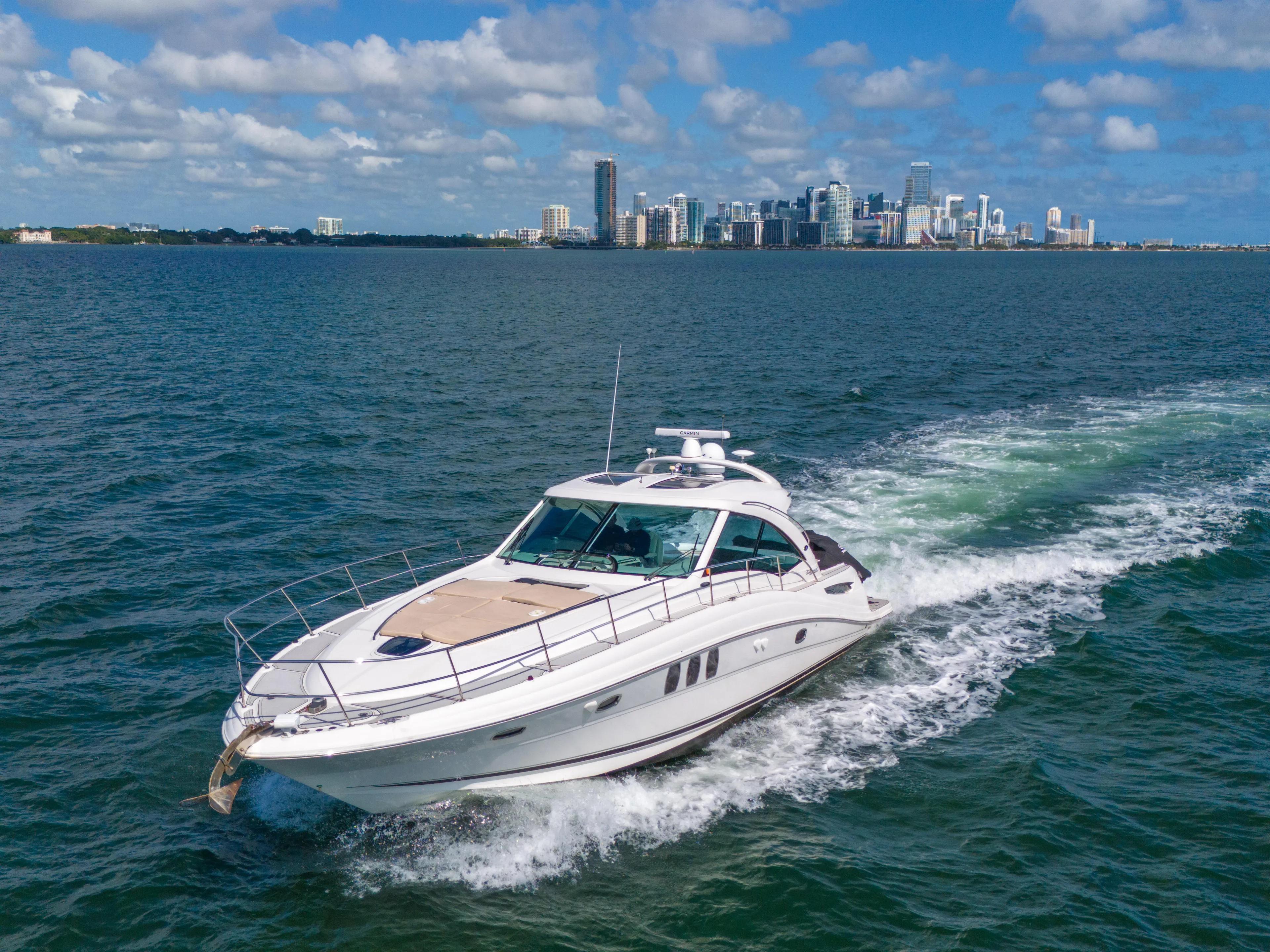  Yacht Photos Pics Sea Ray 500 Sundancer 2010 cruising on ocean with city skyline in background.