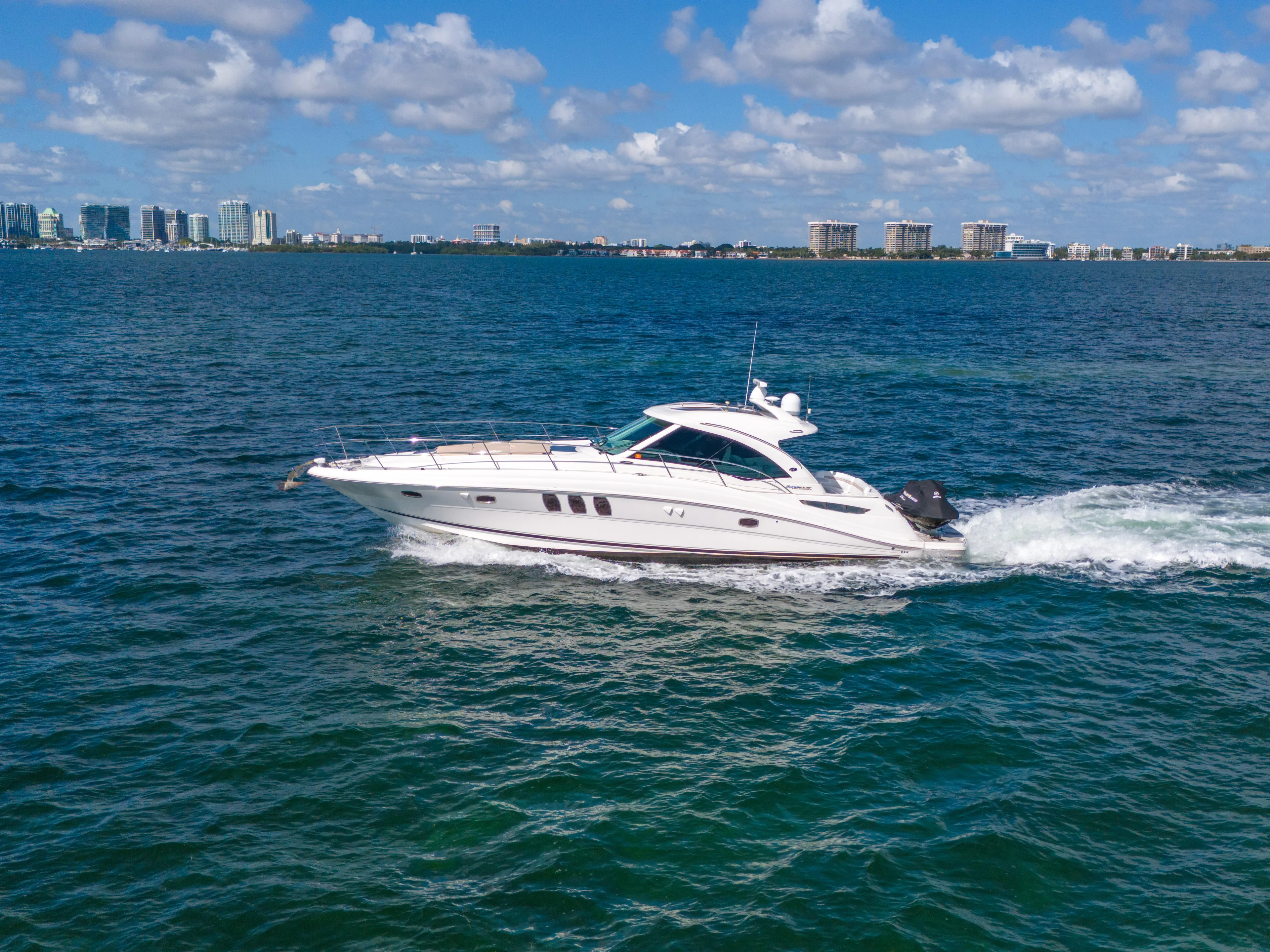  Yacht Photos Pics 2010 Sea Ray 500 Sundancer cruising on blue ocean with city skyline in background.