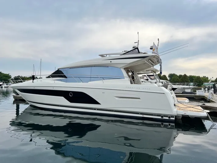  Yacht Photos Pics 2021 Prestige 590 Sport Fly yacht docked in a marina, reflecting on calm water.