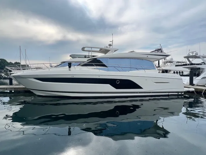  Yacht Photos Pics 2021 Prestige 590 Sport Fly yacht docked at marina under cloudy sky.