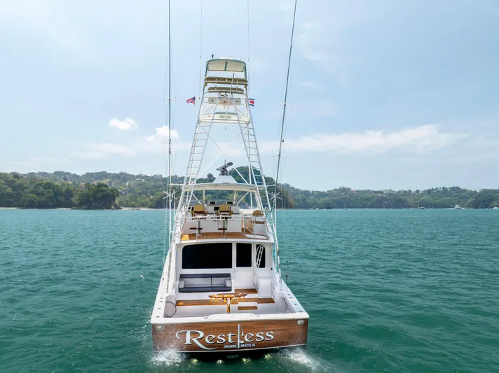 Relentless Yacht Photos Pics 2003 Viking 61 Convertible yacht "Restless" on calm waters, scenic coastal backdrop.