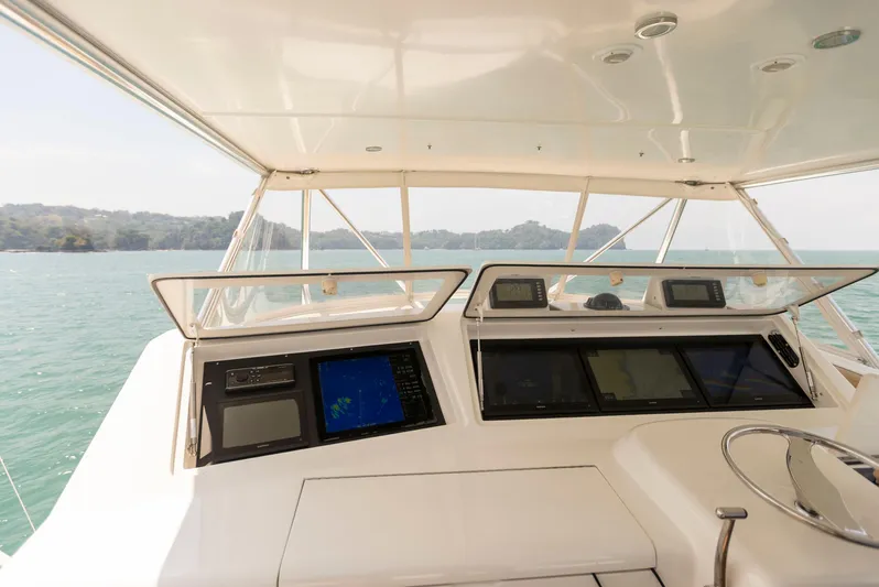 Relentless Yacht Photos Pics Helm of 2003 Viking 61 Convertible yacht with navigation screens, overlooking serene waters.