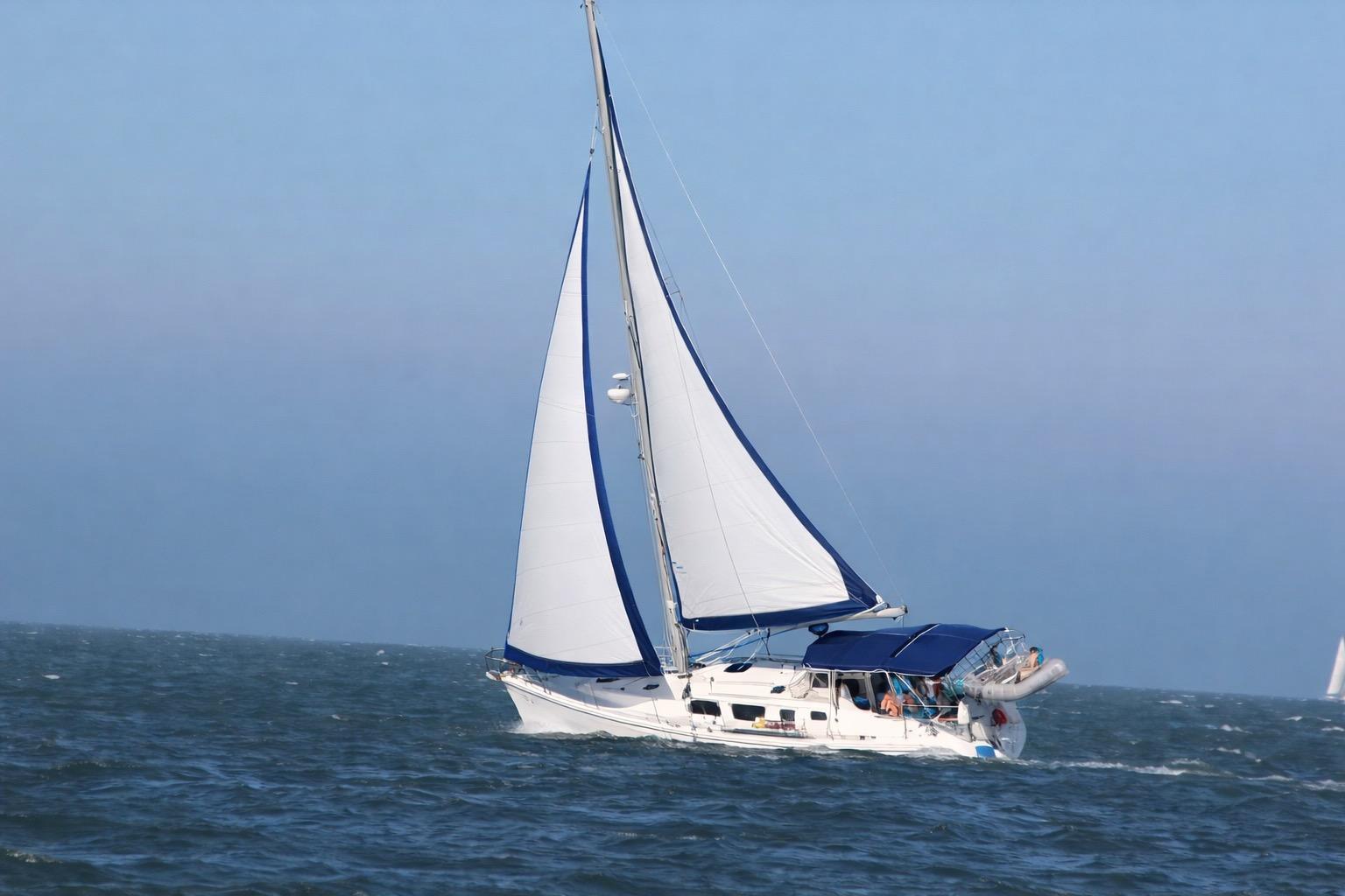 2007 Hunter 44 Deck Salon sailing on open sea with blue sky background.