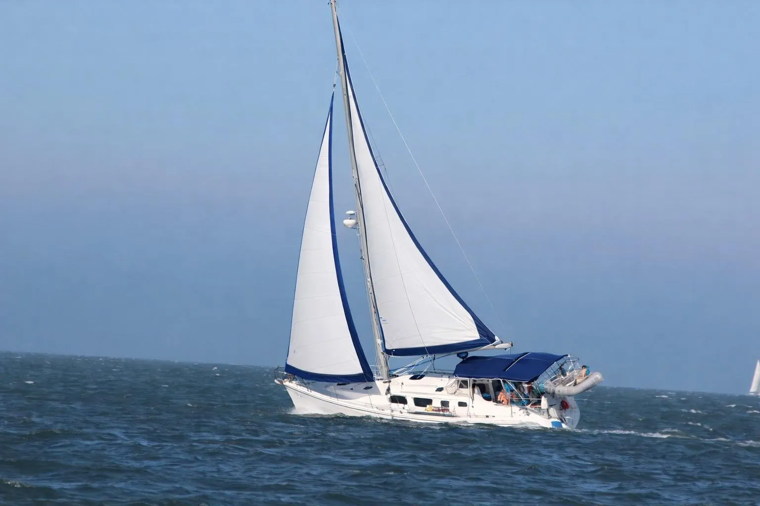2007 Hunter 44 Deck Salon sailing on open sea with blue sky background.