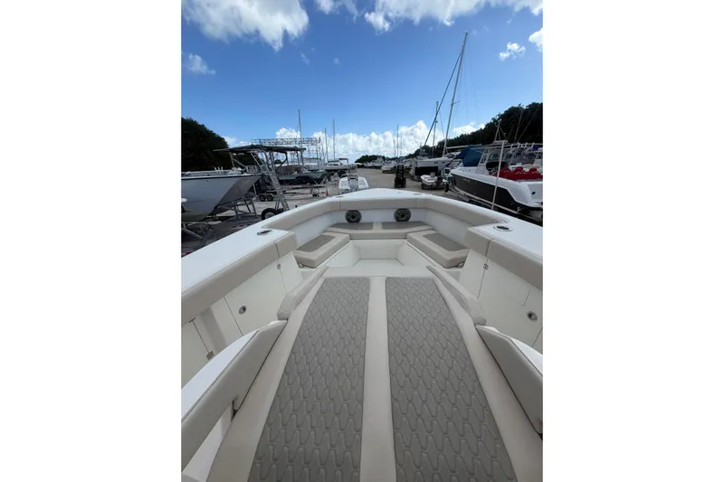  Yacht Photos Pics 2023 Solace 32 CS boat interior with cushioned seating, docked under a blue sky.
