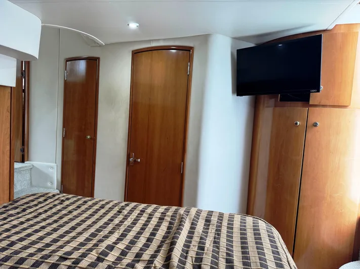  Yacht Photos Pics 2001 Carver 444 Cockpit Motor Yacht interior with wood doors, TV, and checkered bedding.