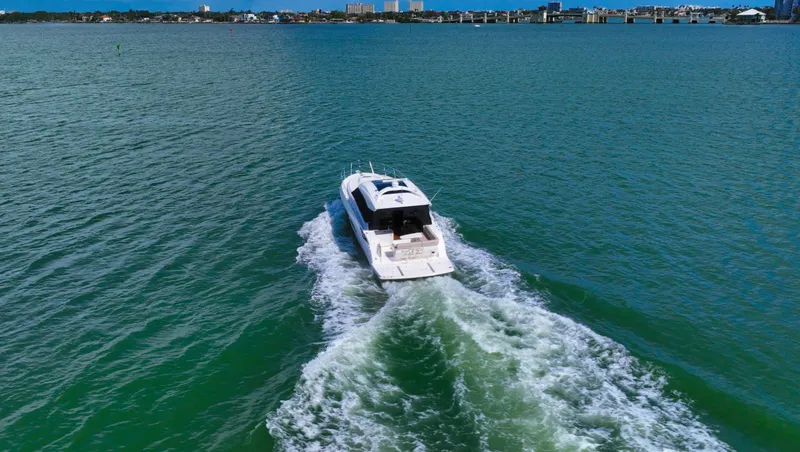 Just In Time Yacht Photos Pics 2016 Sea Ray 470 Sundancer cruising on open water with city skyline in background.